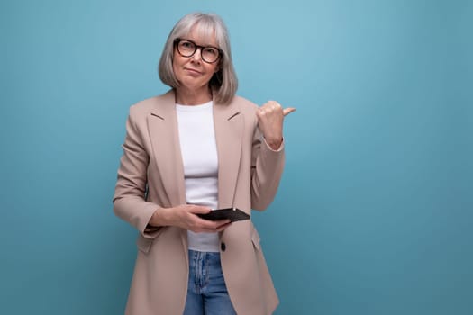mature woman in a stylish image with a smartphone in her hands on a studio background with copy space.