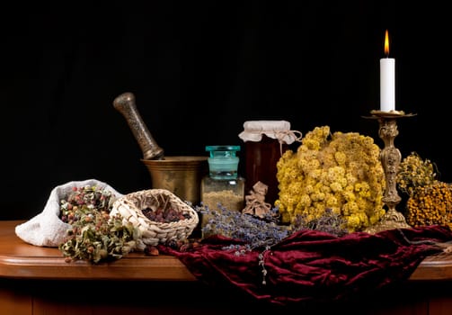 mortar and pestle. on a black background. wooden table. Dried healing herbs, flowers and candles, ritual purification , copyspace Close up of healing herbs alchemist stuff. Old pharmacy, alternative medicine concept.