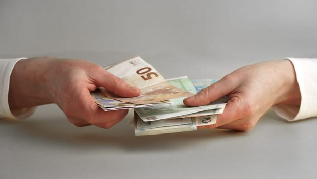 Hands and money. Women's hands hold, count money in euros and dollars isolated on a gray background