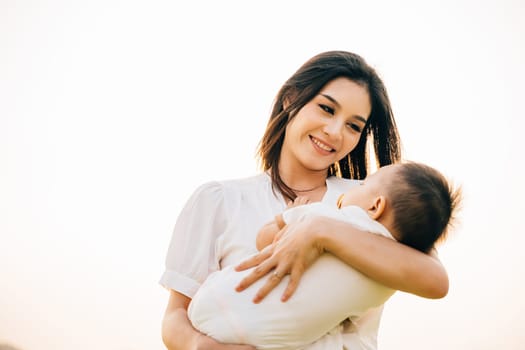 In a quiet park at dusk, a mother holds her sleeping baby, feeling warmth of setting sun. Her face is full of love and contentment as she takes in the beauty of garden. A perfect Mother's Day moment