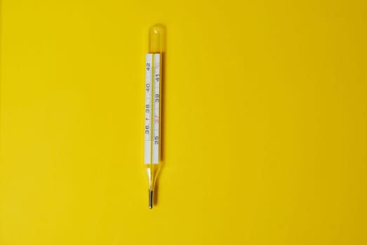 medical thermometer for measuring temperature on a yellow background, top view