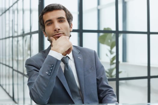 Image of a successful businessman rubbing his beard having an interesting idea while sitting in a modern office