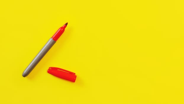 Top view on red marker, cap opened, on yellow board, copyspace for your text on right side.