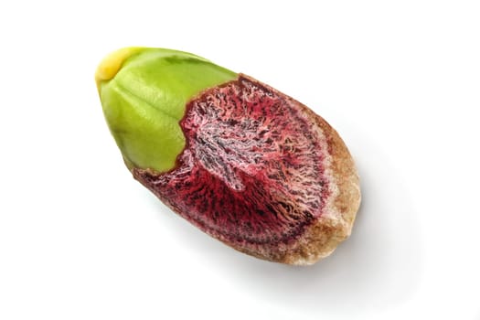 Detail of single pistachio nut, partial peeled, green kernel visible under purple skin, isolated on white background.