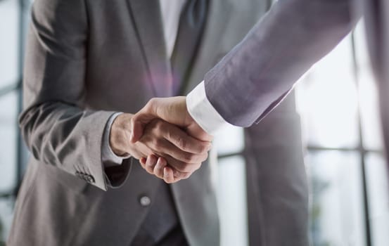Photo of business handshake over workplace in office