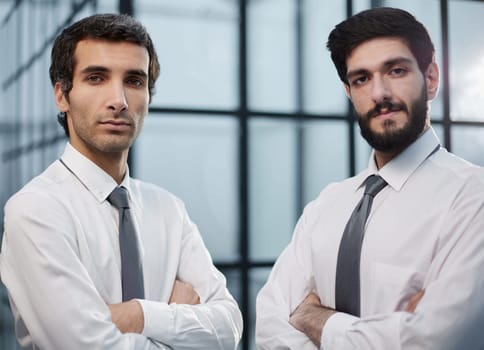 two handsome serious men standing against the backdrop of the office