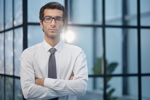 Dedicated to his business. Shot businessman standing with his arms crossed crossed in an office at work.