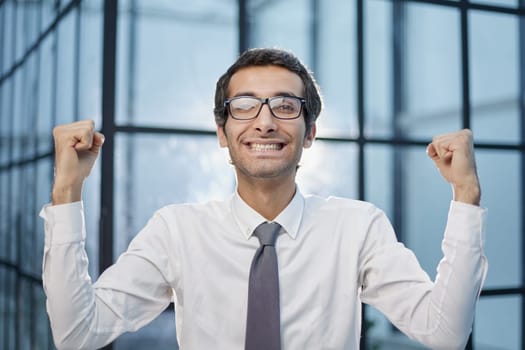 Millennial office worker standing in hallway clenched fists feel overjoyed celebrate career advancement