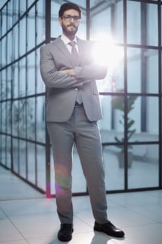 Confident male businessman standing in a modern office.