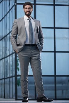 confident young businessman standing with his arms crossed looking at camera