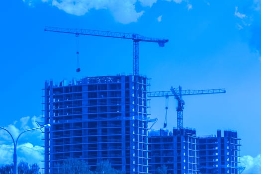 Tower cranes build and development new urban houses architecture industry on blue sky background.