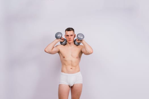 Shirtless bodybuilder holding a dumbell and showing his muscular arms.