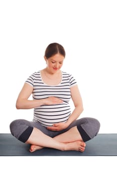Pregnancy yoga exercise - pregnant woman doing asana Sukhasana easy yoga pose embracing her belly isolated on white background