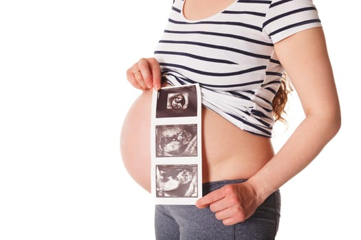 Pregnant woman standing and holding her ultrasound baby scan picture isolated on white