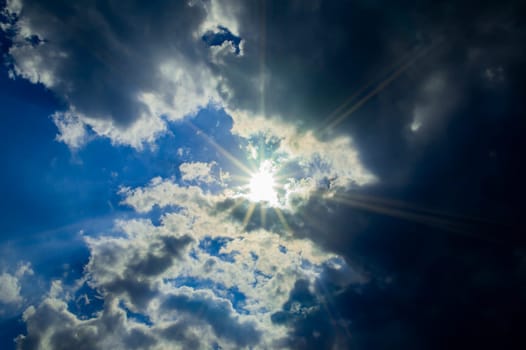 The sun rays break through a thundercloud on a blue sky. Sunbeam in heaven. Thunderclouds. Blue sky. Weather forecast. Climatic conditions. background image. Beautiful landscape.