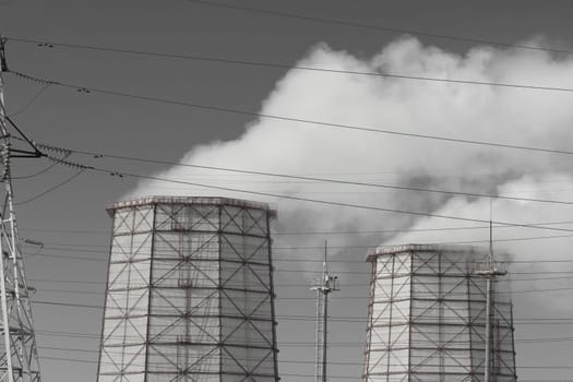 Toxic grey smoke is released from the cooling tower into the atmosphere and pollutes the environment, air and atmosphere. Operation of the industrial heat and power plant.