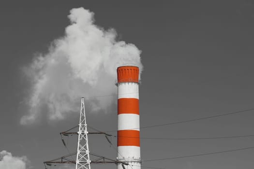 The pipe of the industrial plant emits toxic grey smoke into the atmosphere sky and air. Pollution of the environment and ecology. Thermal power plant power lines high voltage.