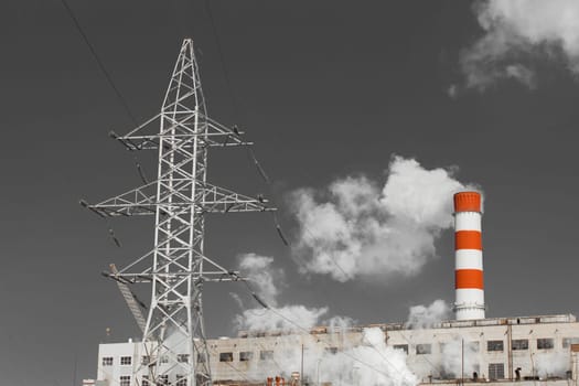 The pipe of the industrial plant emits toxic grey smoke into the atmosphere sky and air. Pollution of the environment and ecology. Thermal power plant power lines high voltage.