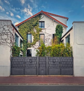 Green eco friendly home. House facade with different plants and trees growing in front of it. Environment, conservation and greening concept