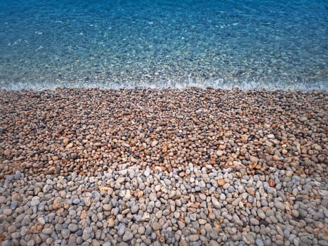 Pebble rocks beach and blue sea water texture