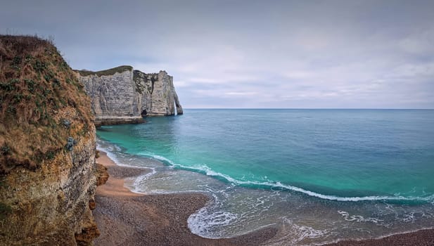 Sightseeing view to the wonderful cliffs of Etretat washed by the waves of the blue sea water, La Manche Channel. Famous Falaise d'Aval coastline in Normandy, France
