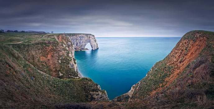 Sightseeing panoramic view to the Porte d'Aval natural arch cliff washed by Atlantic ocean waters at Etretat, Normandy, France. Beautiful coastline scenery with famous Falaise d'Aval
