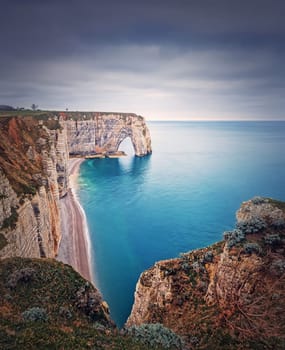 Idyllic view to Porte d'Aval natural arch at Etretat famous cliffs washed by Atlantic ocean, Normandy, France. Sightseeing coastline scenery, beautiful natural bay with sand beach