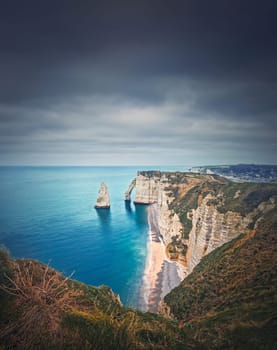 Falaise d'Aval limestone cliffs washed by La Manche channel waters. Beautiful coastline view to the famous rock Aiguille of Etretat in Normandy, France