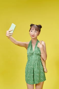 Portrait of young cheerful woman in summer wear makes selfie on smartphone