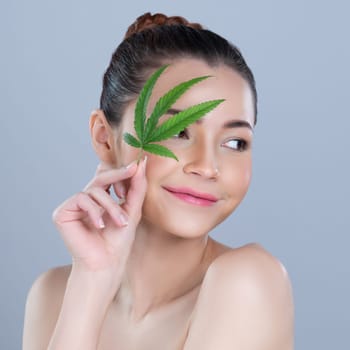 Closeup glamorous beautiful woman with soft make up and flawless smooth clean skin holding green leaf. Cannabis skincare cosmetic product for natural skin treatment concept in isolated background