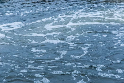 The surface of the lake water with a foam trace is a natural background. The process of filtering water of a dirty environment trail.