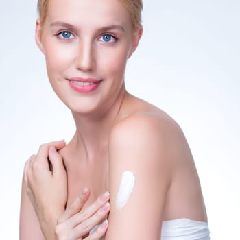 Closeup personable beautiful woman putting skincare moisturizer cream on her arm looking in camera in isolated background as concept for beauty care treatment. Female model applying lotion on her body