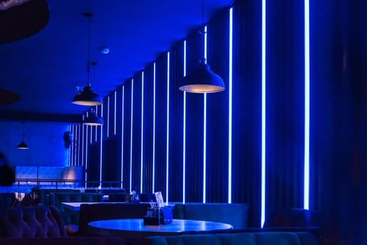 Modern abstract interior of a nightclub with neon blue lighting on the walls.