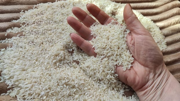 White cereals rice and hand of woman in it. Food for background and texture. Product and food which can be stored for a long time. Partial focus