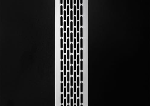 Ventilation air system modern ventilation cooling grille mounted in a black wall, close-up.