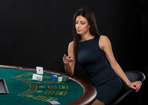 sexy woman with poker cards and chips. Female player in a beautiful black dress, throws a card. Two aces