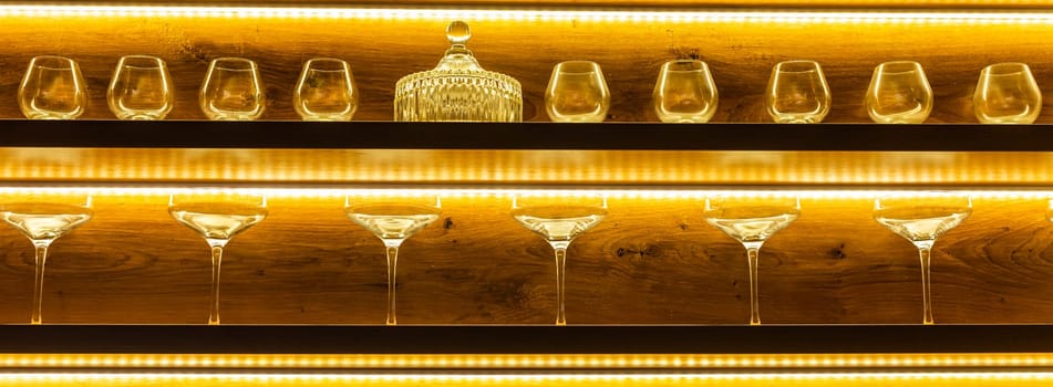 Glasses of wine. Glasses hanging above the bar in the restaurant. Empty glasses for wine. Wine and martini glasses in shelf above a bar rack in restaurant. night life