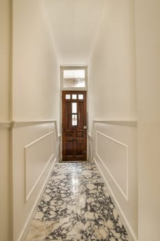 a long hallway with marble flooring and white trim on the walls, leading to an open door that leads to another room