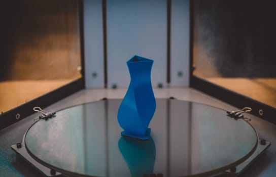 3D printer close up. Bright blue object printed by 3d printer. Modern 3D printer printing an object from the hot molten. Concept progressive additive technology for 3d printing.