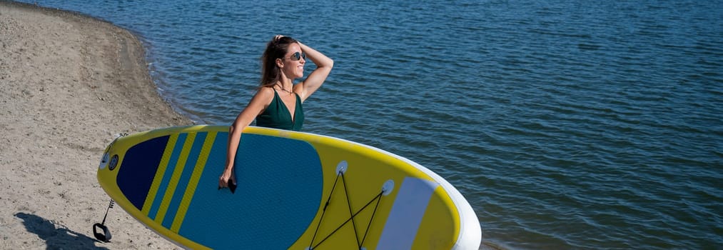 Caucasian woman walks along the beach and carries a sup board on the river in the city. Summer sport