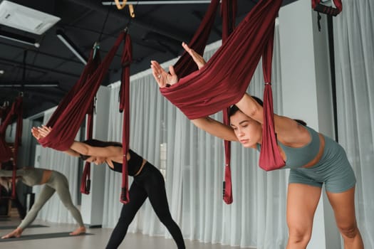 A group of women play sports on hanging hammocks. Fly yoga in the gym.