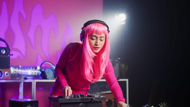 Musician standing at dj table mixing sound using professional mixer console, playing techno remix for fans during eletronic concert. Asian artist performing new album, enjoying nightlife