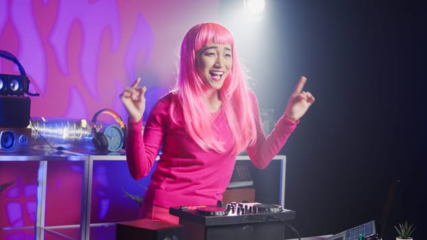 Dj artist using professional mixer console in nightclub, mixing techno sound creating unique remix for fans. Asian performer with pink hair playing musical album, performing eletronic music