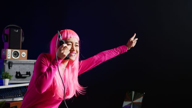 Musician having fun during performance talking with fans, mixing and mastering electronic sound using professional mixer console. Dj artist with pink hair performing music in club at nightime