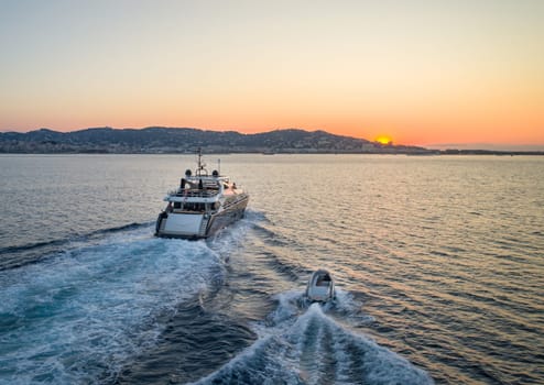 A beautiful super yacht motors off into a sunset with the tender in tow