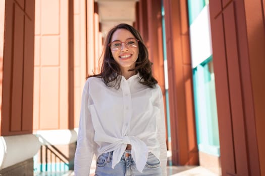 Successful smiling business woman wearing eyeglasses. Modern businesswoman smile standing outdoor dressed white shirt and jeans. Business woman happy positive emotions