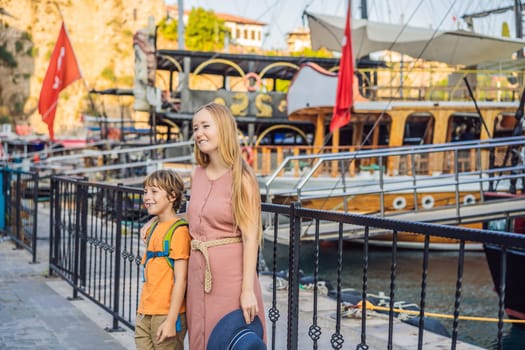 Mom and son tourists in Old town Kaleici in Antalya. Turkiye. Panoramic view of Antalya Old Town port, Taurus mountains and Mediterrranean Sea, Turkey. Traveling with kids concept.