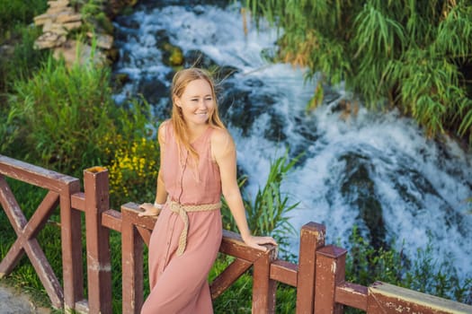 Beautiful woman with long hair on the background of Duden waterfall in Antalya. Famous places of Turkey. Lower Duden Falls drop off a rocky cliff falling from about 40 m into the Mediterranean Sea in amazing water clouds. Tourism and travel destination photo in Antalya, Turkey. Turkiye.