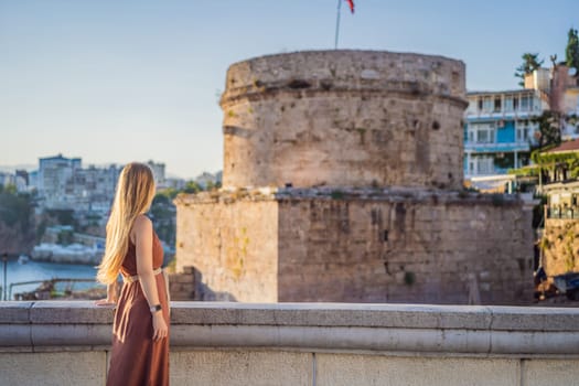 Woman tourist on background of Hidirlik Tower in Antalya against the backdrop of the Mediterranean bay of the ancient Kaleici district, Turkey. Turkiye.