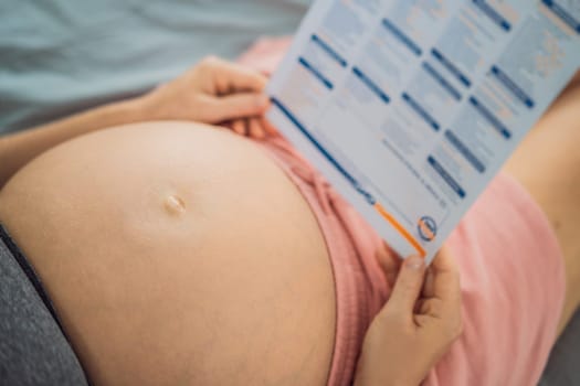 A pregnant woman looks at the results of a blood test printed on paper.